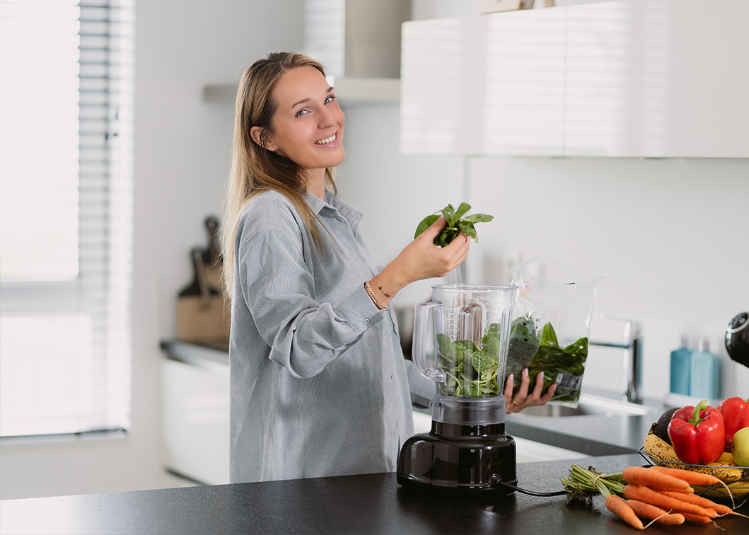 De coach houdt greens voor een blender